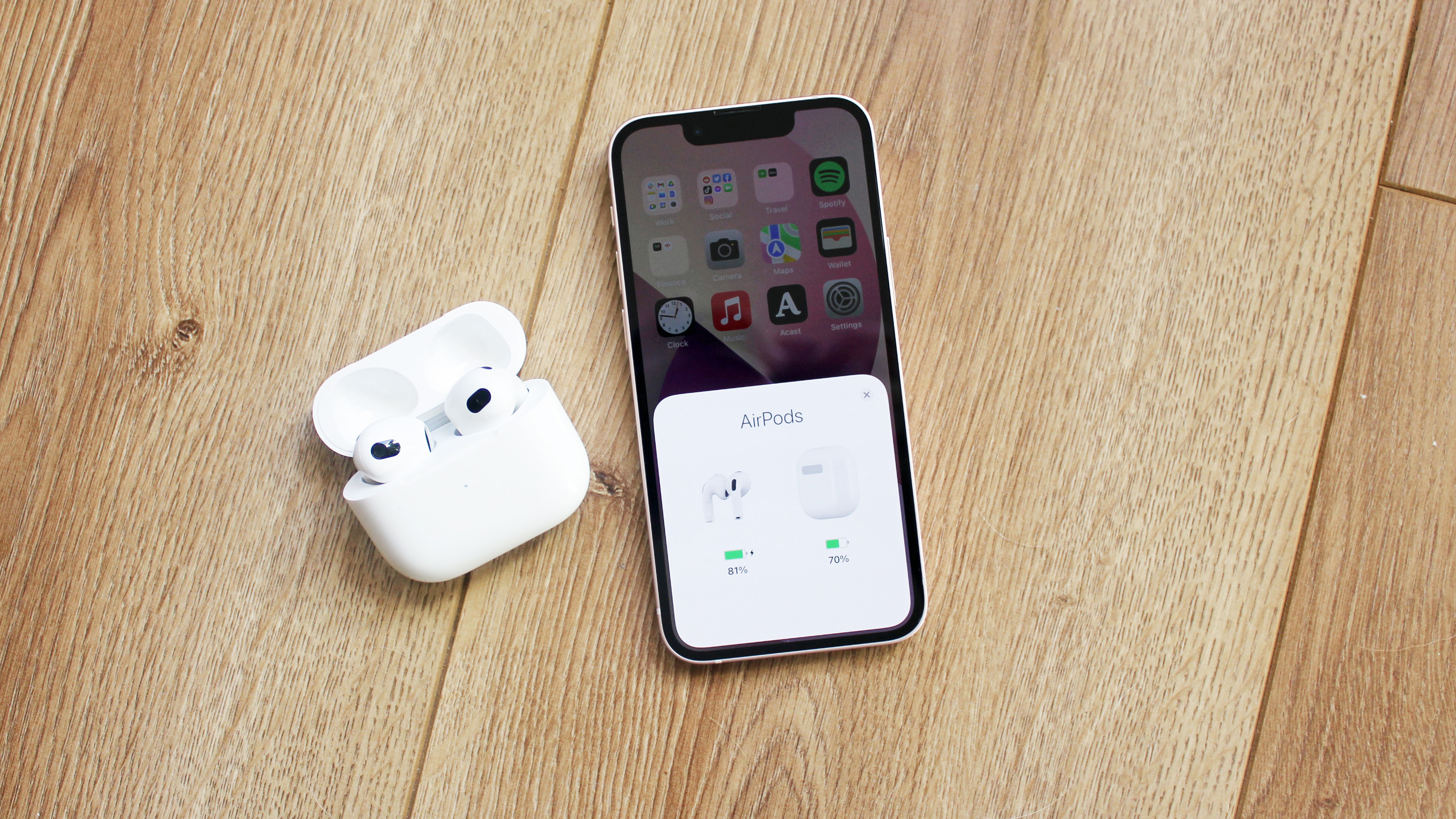 the airpods 3 with an iphone 13 mini displaying their battery life