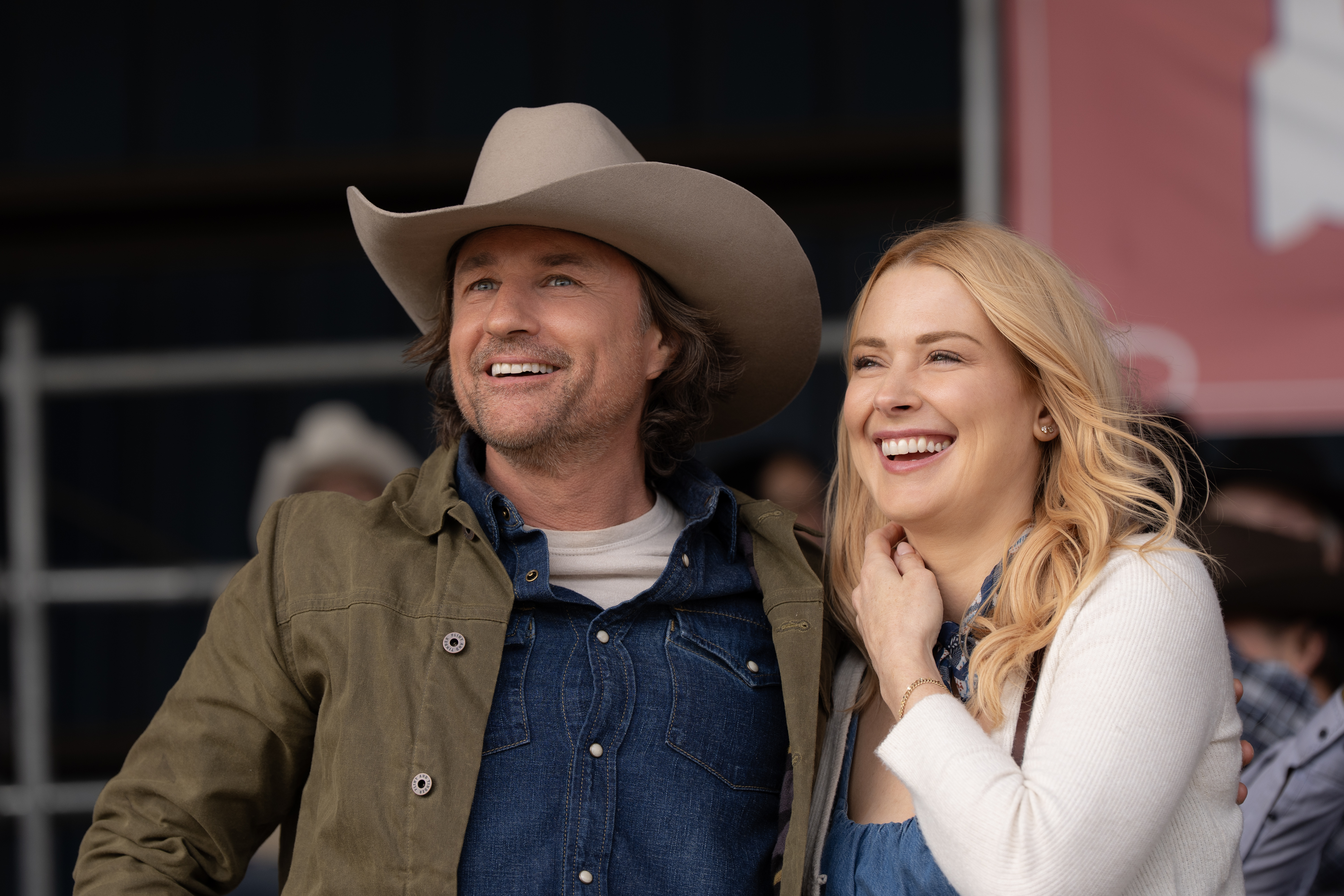 Martin Henderson as Jack Sheridan and Alexandra Breckenridge as Melinda Monroe smiling in the stands at a rodeo in virgin river season 7