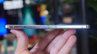 En mobiltelefon av typen Samsung Galaxy Z Flip 5 holdes opp av en hånd.