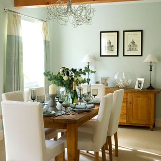 dinning room with white wall wooden dinning table with chairs frames on wall and wooden cabinet