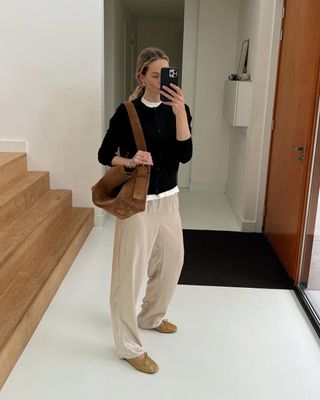 Fashion influencer Anouk Yve taking a mirror selfie wearing a chic fall outfit with a suede bag.