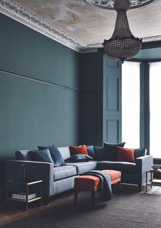 Living room with sectional and dark walls and chandelier