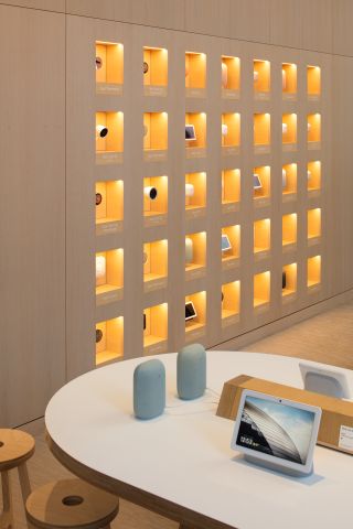 A wooden wall with small square alcoves showing Google's Nest offering