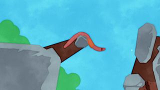 A worm wriggles over a rock against a blue sky background.