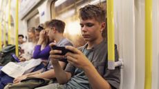 A teenage boy playing on a device on the London Underground