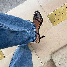 French fashion influencer Sylvie Mus wears Madewell's The Milano Heeled Sandal with relaxed blue denim jeans.