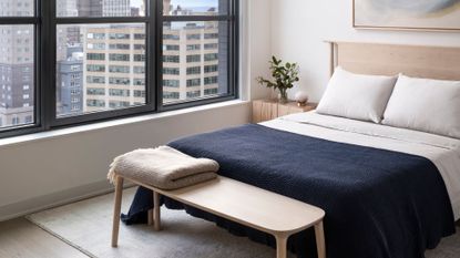 A bedroom with a throw blanket and a weighted blanket on a bench at the foot of the bed