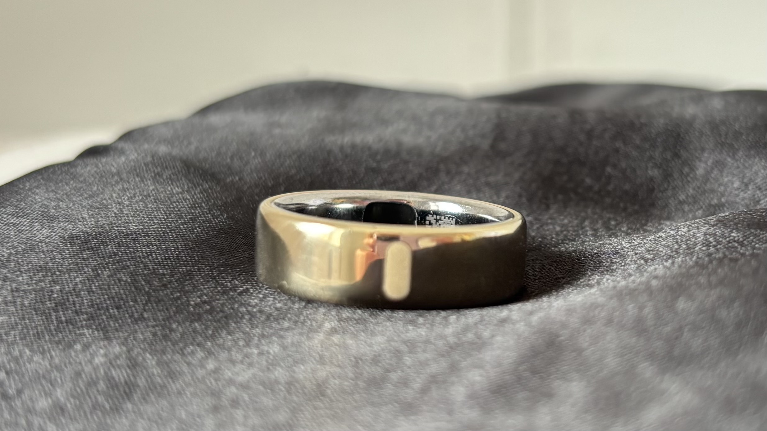 The Oura Ring 5 positioned on a satin sleep mask to show the white indicator mark.