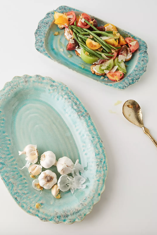 two blue platters containing garlic bulbs and salad 