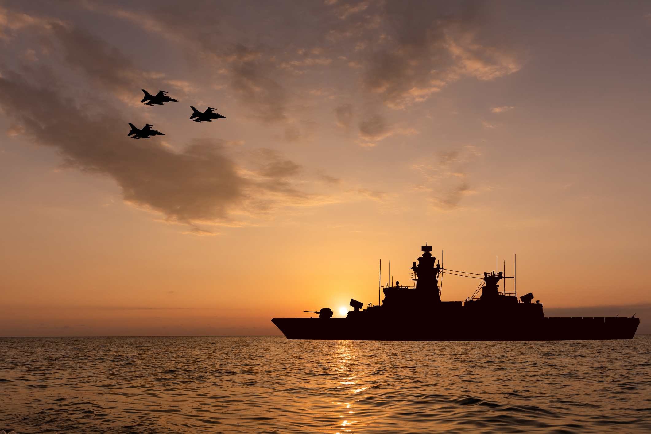 Warship and fighter jets at sunset