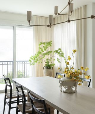 dining room with pale wood table and white curtains
