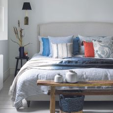 coastal inspired bedroom with striped bed linen colourful cushions, natural materials and basketware 