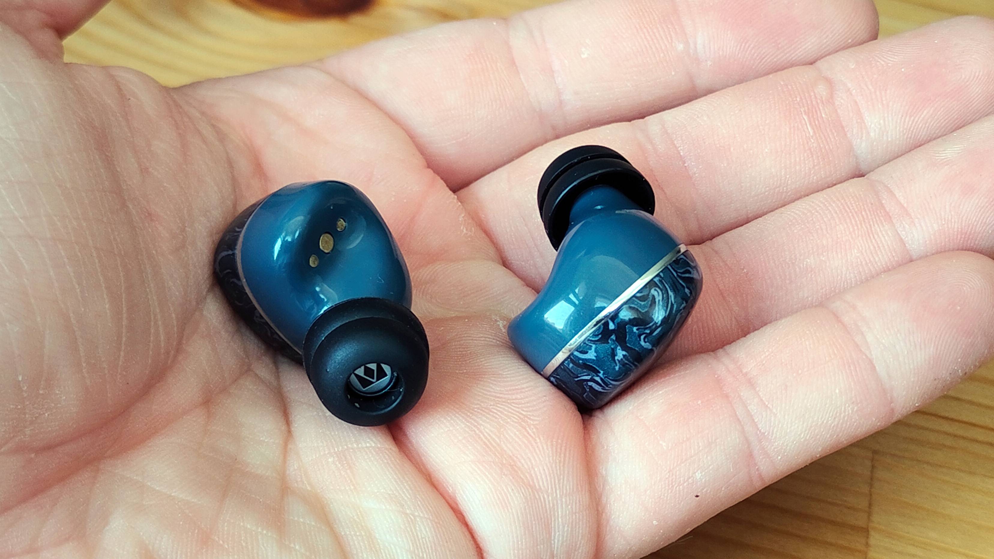 The Noble Osprey earbuds in a man's hand.