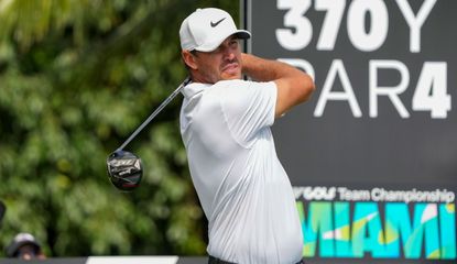Koepka hits his driver in front of an LIV Golf board