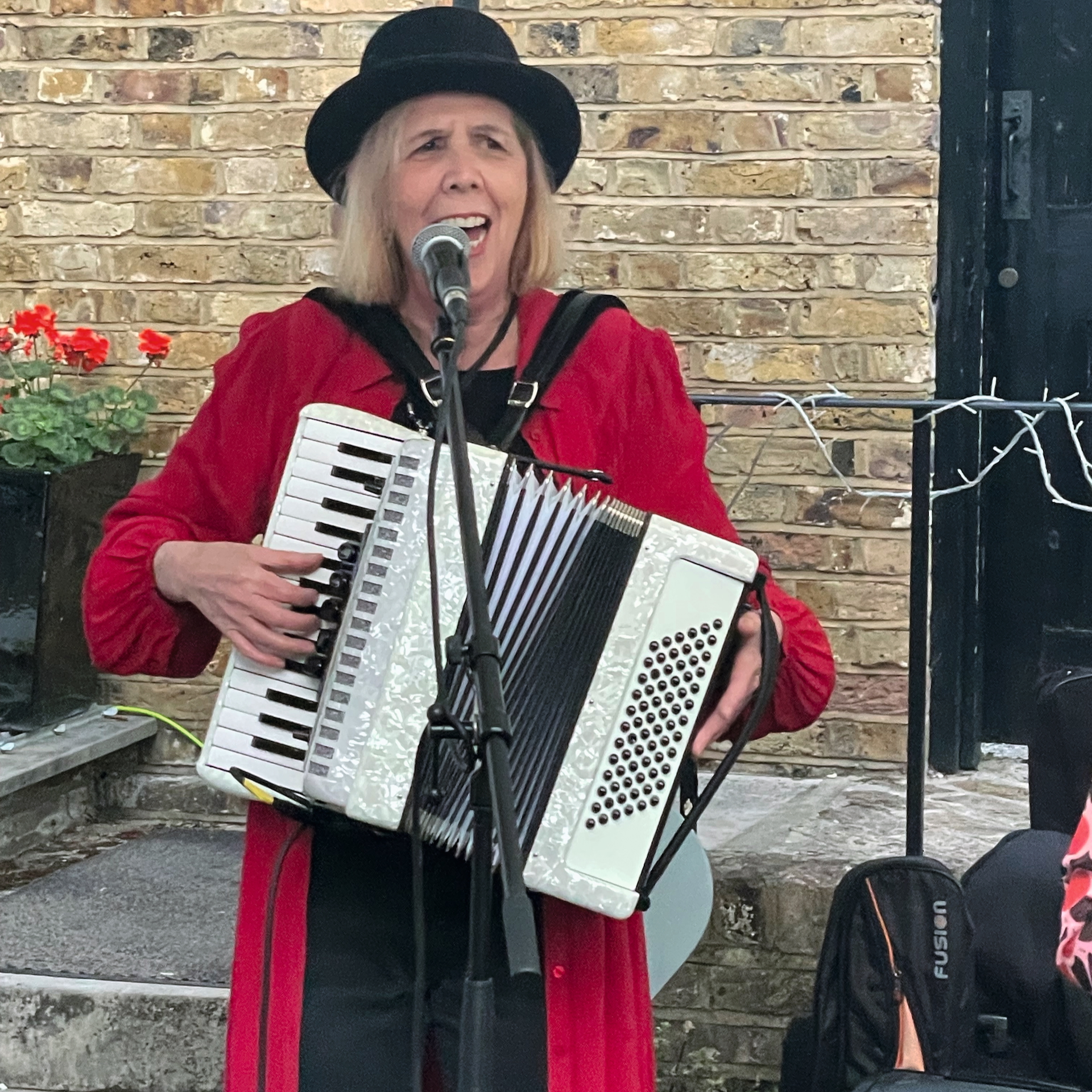 Heather Gilmore from Ukadelix, playing an accordion and singing into a microphone