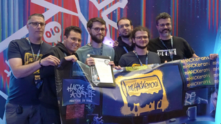 a team of people hold a trophy and a flag that reads "hack-a-sat"