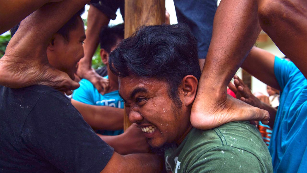 Children from the Indonesian Bawean community compete for prizes by climbing a 'panjat pinang' - a pole smeared with butter