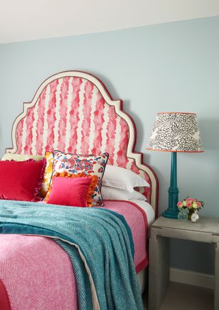 a loud and colorful bed with blue walls and a funky bedside lamp, a great bedroom idea