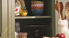 Charming vintage-inspired kitchenware from Molly Yeh's new Anthropologie collaboration styled atop a set of exposed olive green kitchen shelves