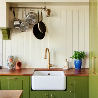 butler sink in country kitchen with green cabinets and panel splashback