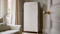Joseph Joseph eclipse drying rack in a white living room with white couch, large windows with white curtains, and open white door.