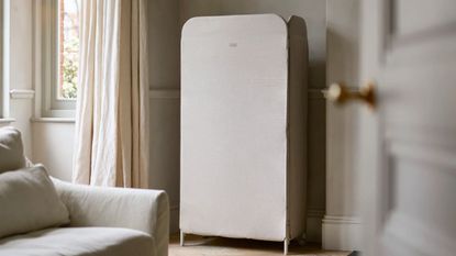 Joseph Joseph eclipse drying rack in a white living room with white couch, large windows with white curtains, and open white door.