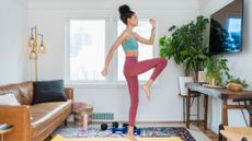 Woman exercising in her living room in front of a wall-mounted TV