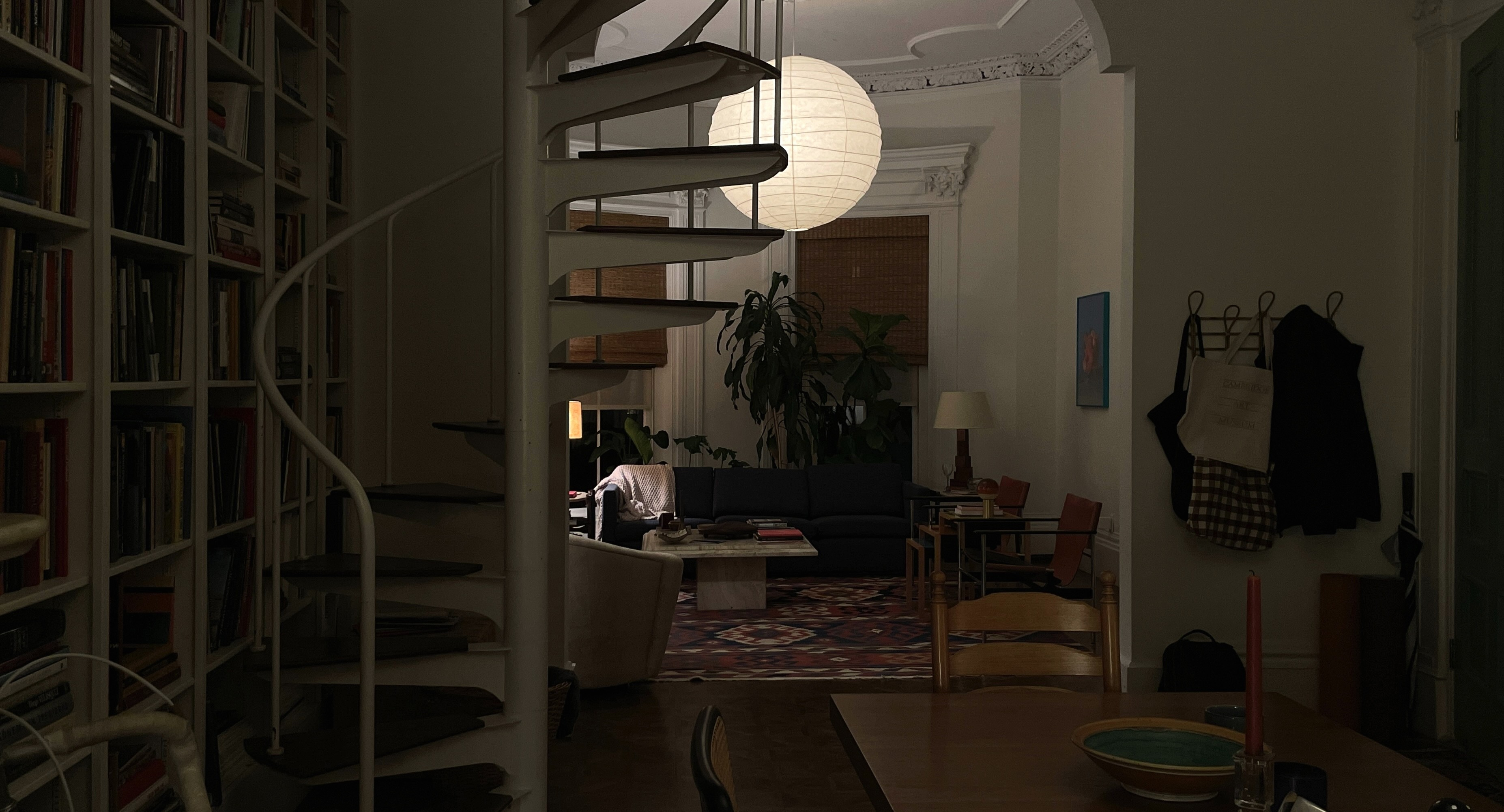 A series of interior shots of an art and objects-filled, dimly lit apartment, a museum's gallery rooms, an empty dance rehearsal room, and colorfully decorated office spaces.