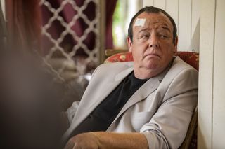 Danny Sheridan (Les Dennis) sits in an armchair, looking uncomfortable, with a bandage on his forehead