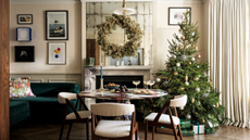 a dining room with a round dining table and three dining chairs, a Christmas tree, and a fireplace with a large wreath above it