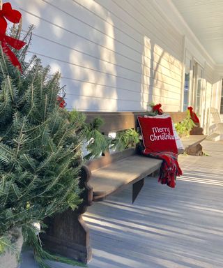 Minimalist understated Christmas porch decor with Christmas trees festive pillows and throws