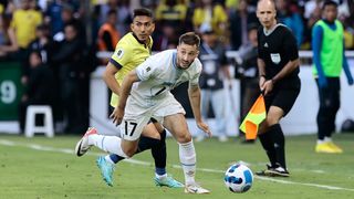 Matias Viña (R), in white kit, takes control of the ball with Rodrigo Paz Delgado, in yellow and black, not far behind, during Uruguay vs Ecuador.