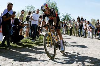 Image shows Wout van Aert racing on cobbles.