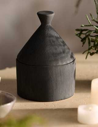 ridged black stoneware pot containing a candle inside