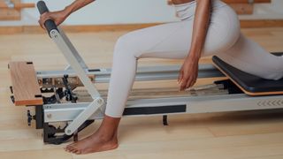 Reformer Pilates machine with woman stretching out legs, demonstrating what is reformer Pilates