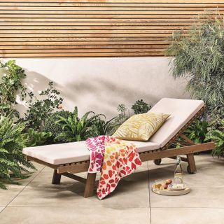 Sun lounger in garden leopard print beach towel summertime with cushion in garden patio setting fence