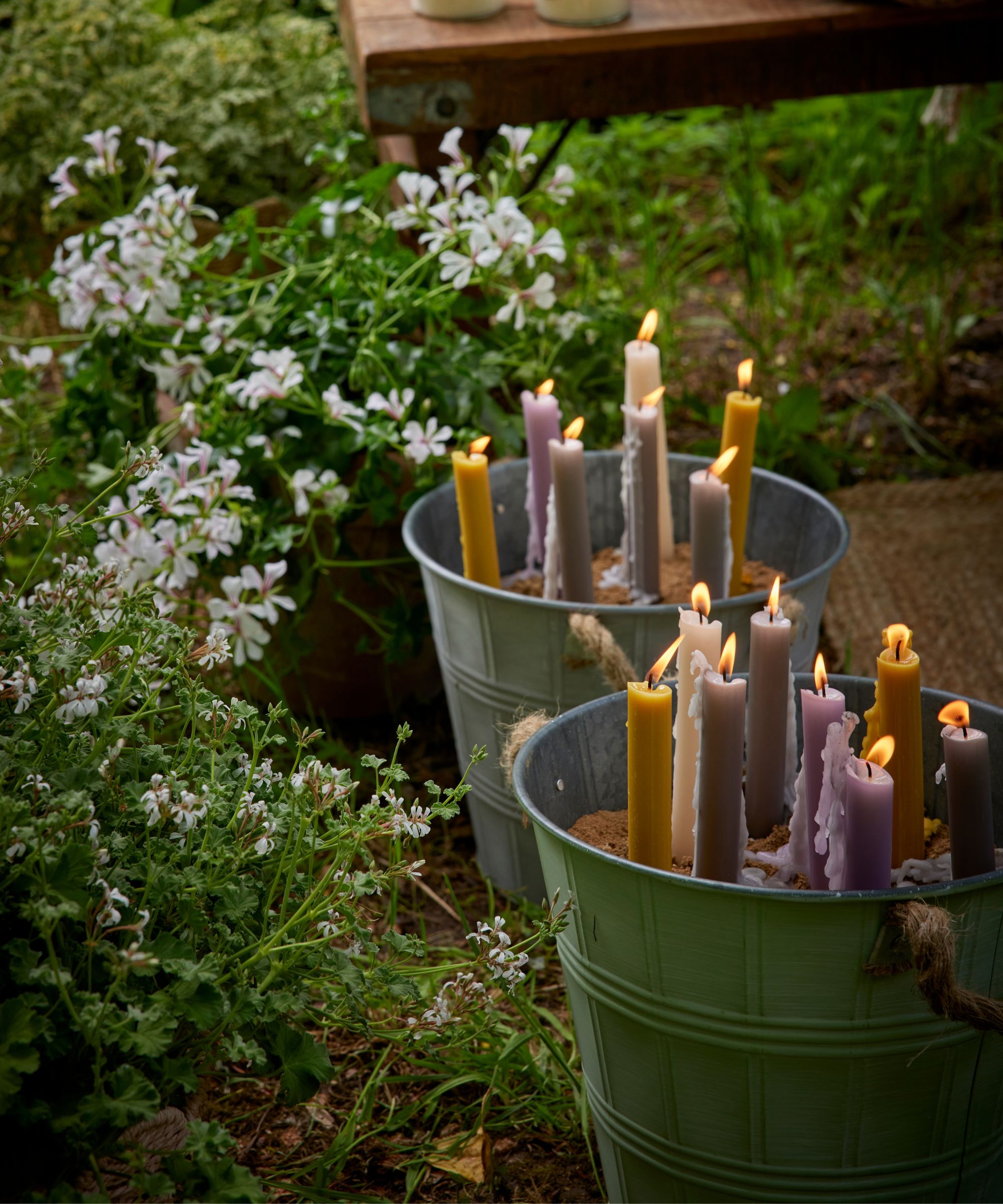 garden greenery with buckets filled with sand and candles