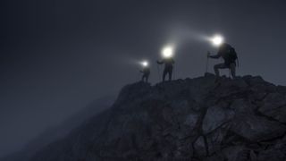 mountaineers on an adventure on a mountain ridge with light beams from head torches