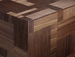 Detail shot showing a corner of a bedside table made of walnut and featuring an intarsia patterned motif