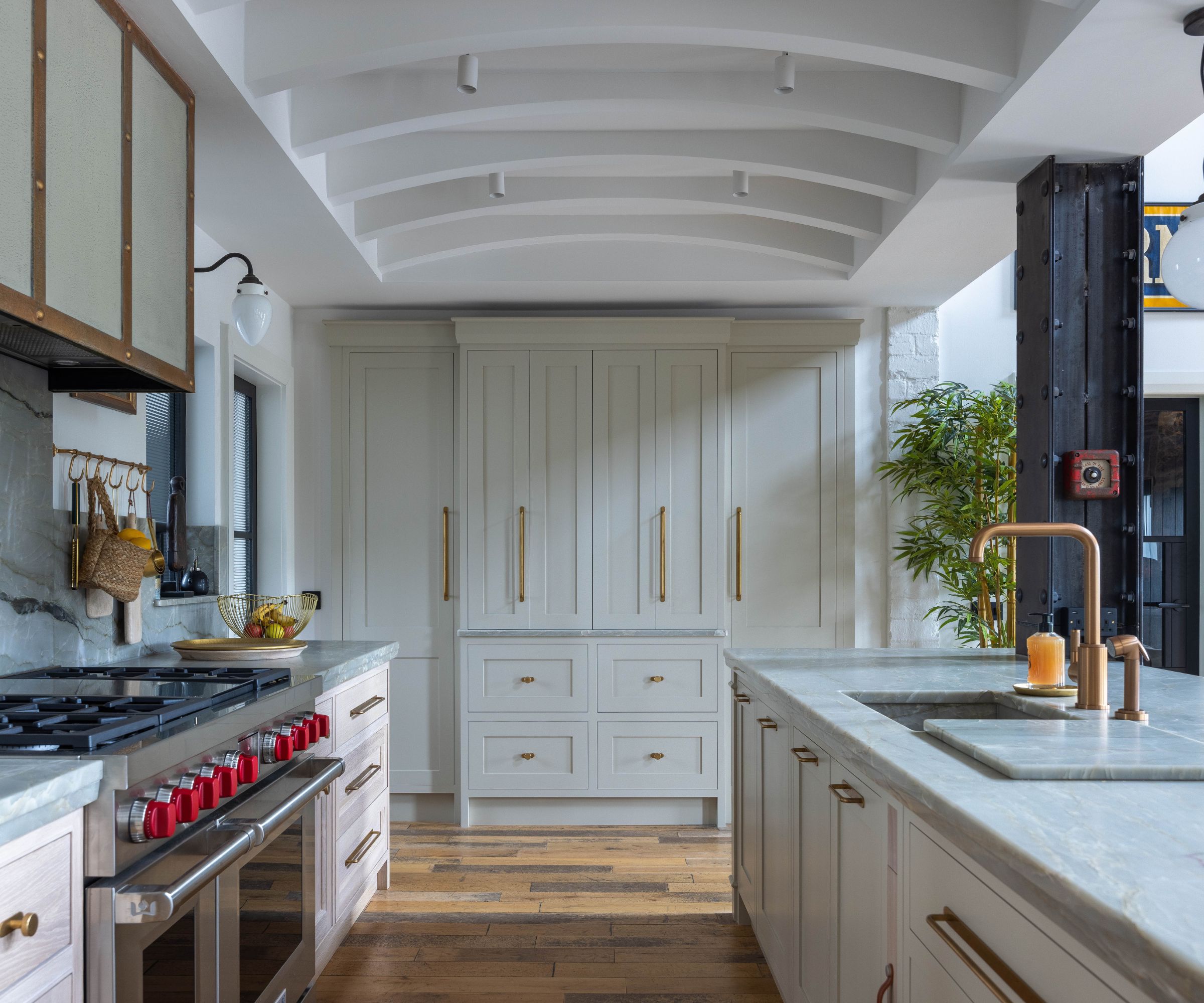 Kitchen with cream painted cabinets and gold hardware, steel stove, marble island with sink