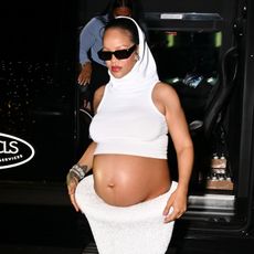 Rihanna wearing a white skirt set with a white hood
