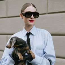 a woman with a bright red lip wearing sunglasses and a slicked back bun - best by terry products