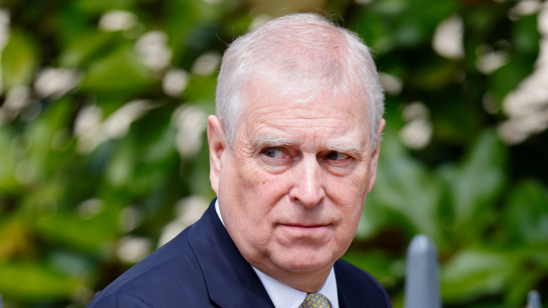 Prince Andrew wearing a blue suit making a serious expression