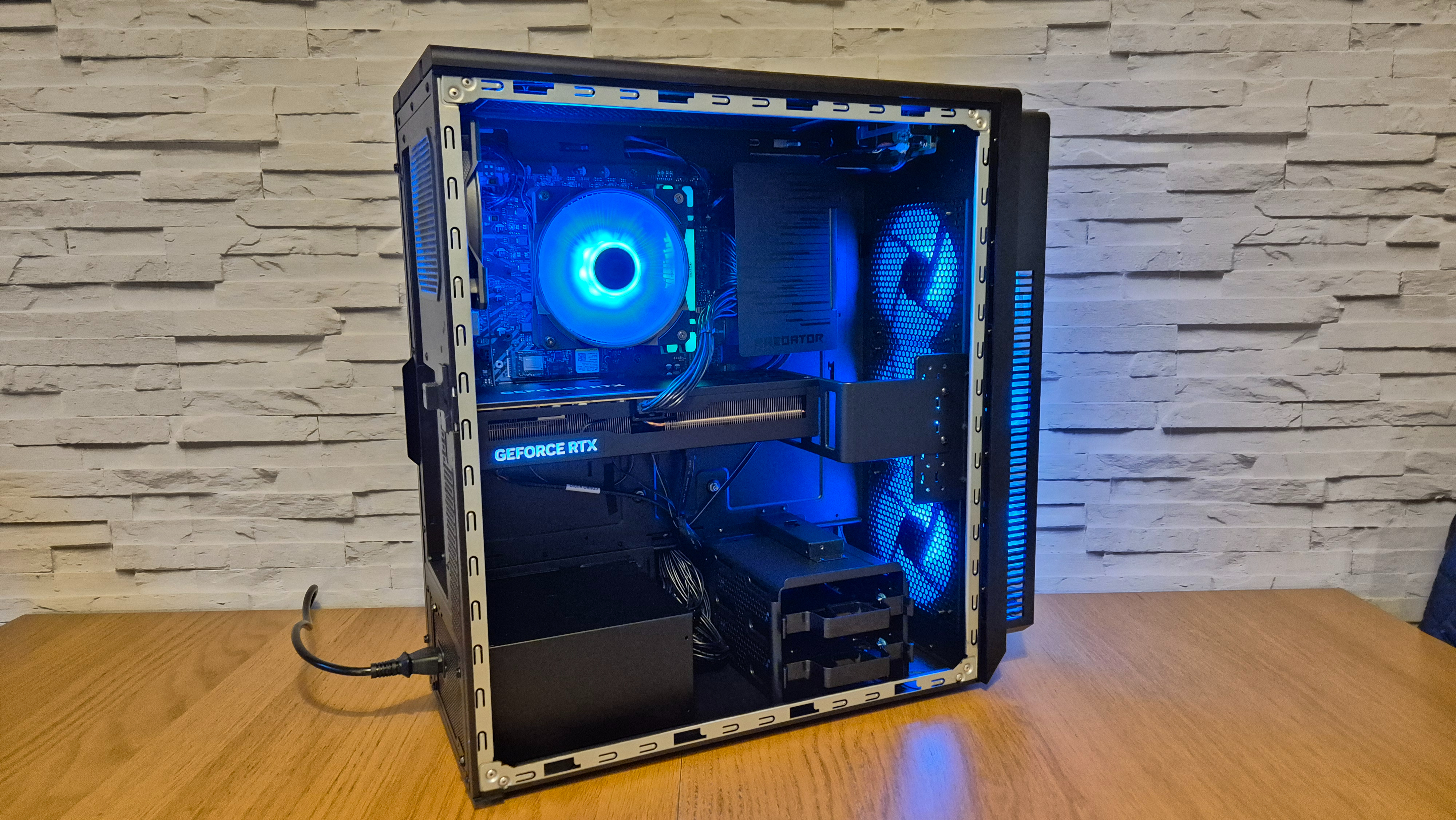 The inside of an Acer Predator Orion 5000 gaming PC sitting on top of a wooden surface infront of a white brick effect wall