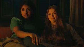 Avantika and Larsen Thompson's characters sit next to each other in a candlelit room in a scene from the movie Tarot.