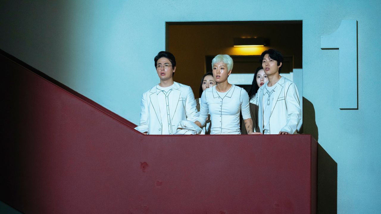 a group of people dressed in white (Park Jeong-min as Seventh Floor, Lee Zoo-young as Second Floor, Ryu Jun-yeol as Third Floor) stand on a balcony next to a number 1 sign, in &#039;The 8 Show&#039;