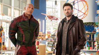 dwayne the rock johnson and chris evans stand in a display room filled with toys, in a still from red one