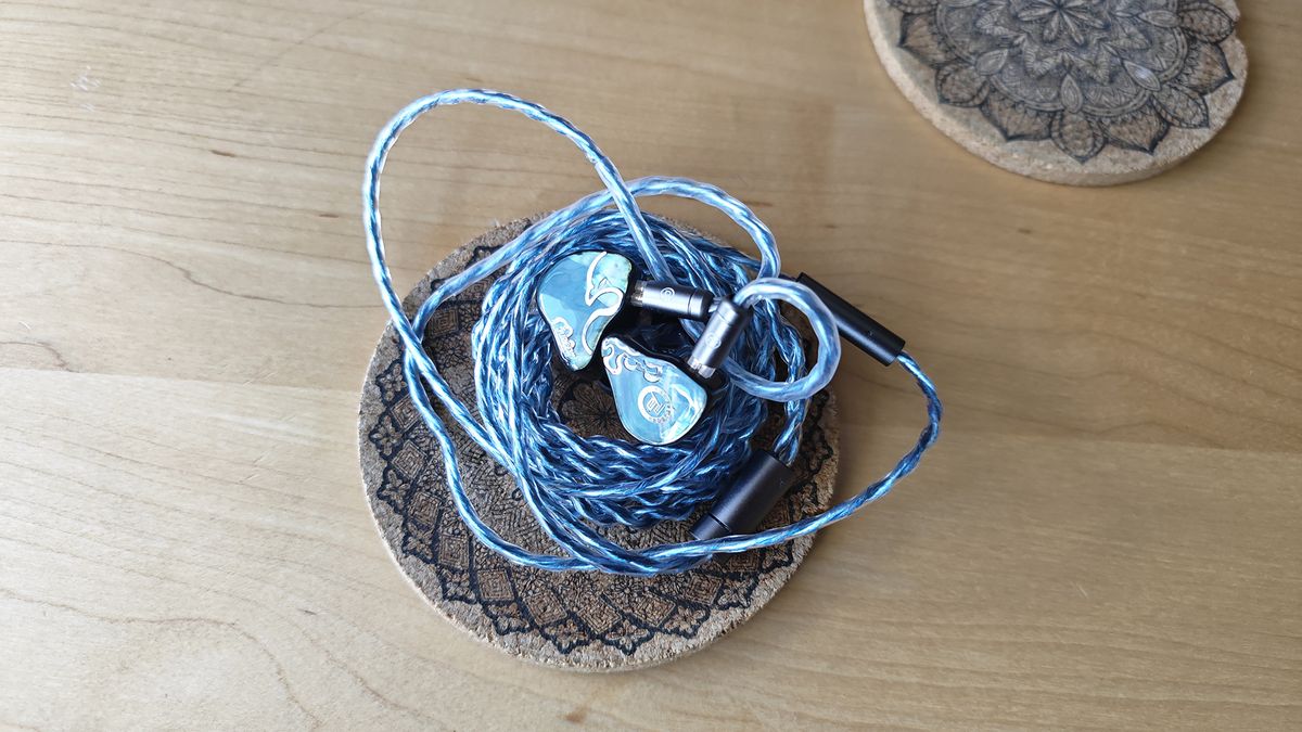 The Juzear Defiant, blue IEMs on a cork coaster.