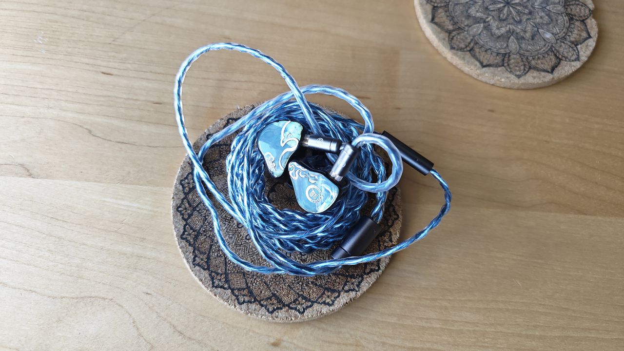 The Juzear Defiant, blue IEMs on a cork coaster.