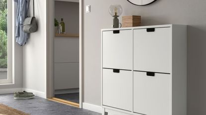 White minimalist IKEA shoe storage cabinet styled inside of a light gray entryway area